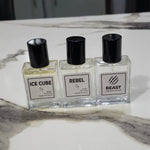 Three clear glass perfume bottles with black caps and white labels reading ICE CUBE, REBEL, and BEAST, arranged on a white marble surface.4